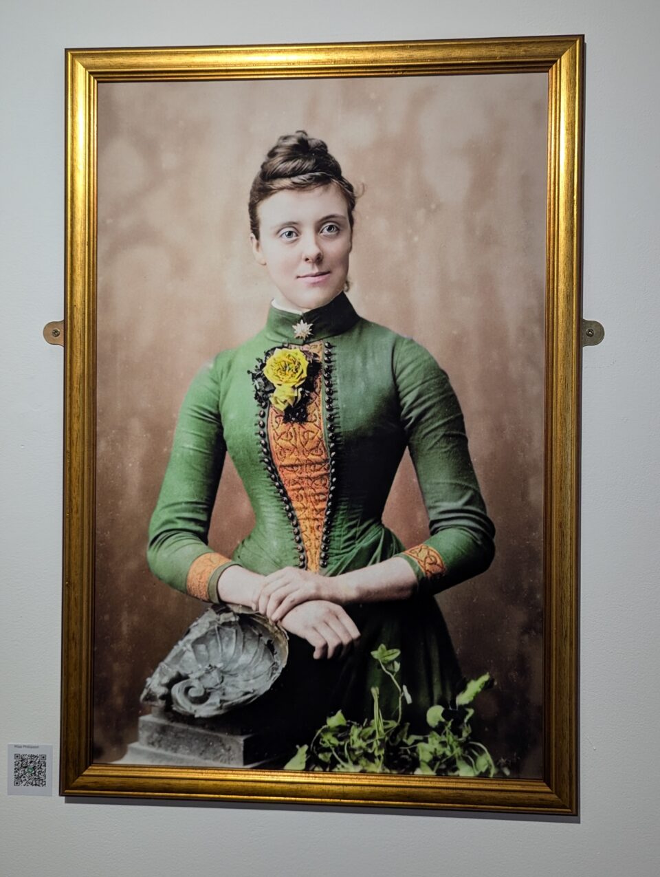 Large framed portrait of a woman in a fitted green dress with orange detailing and yellow flowers.