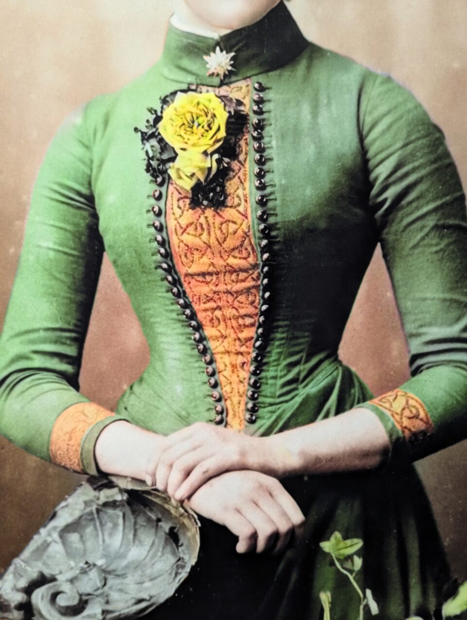 Close-up of the green dress in the portrait, showing orange patterned fabric, black buttons and yellow flowers.